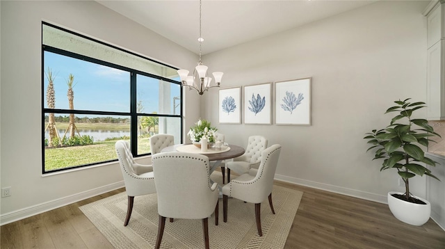 dining area with hardwood / wood-style flooring, a chandelier, and a water view