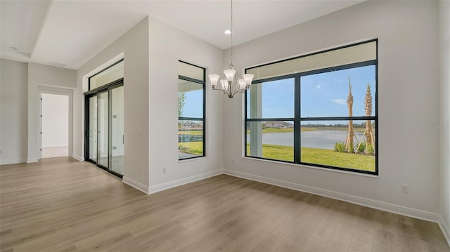 spare room featuring a notable chandelier, light hardwood / wood-style flooring, and a water view