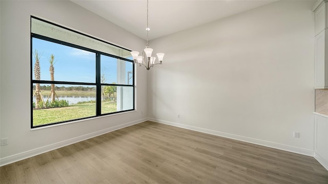 unfurnished room with wood-type flooring, a chandelier, and a water view