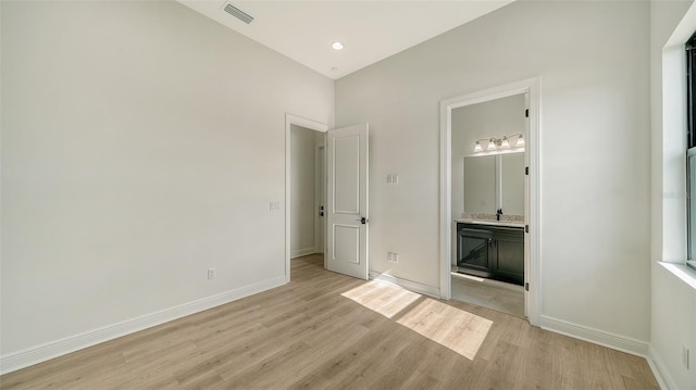 unfurnished bedroom with light hardwood / wood-style flooring and ensuite bath