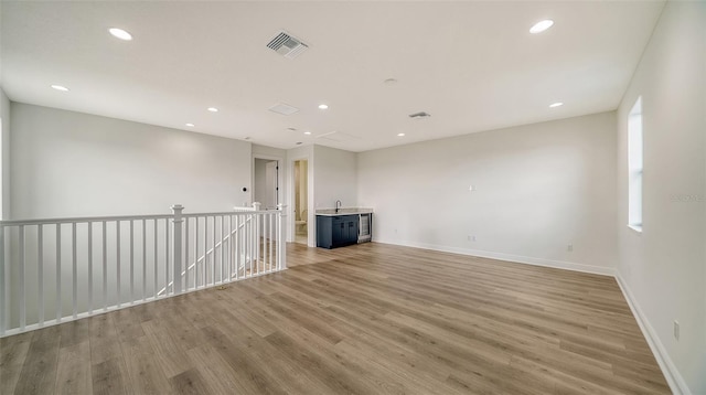 unfurnished living room featuring wood-type flooring and sink