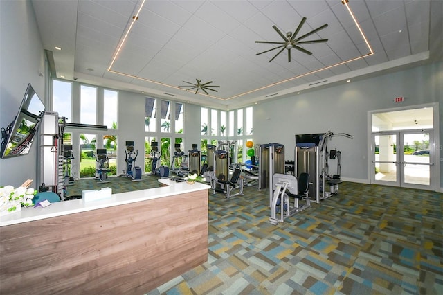 gym with ceiling fan, carpet, and a high ceiling