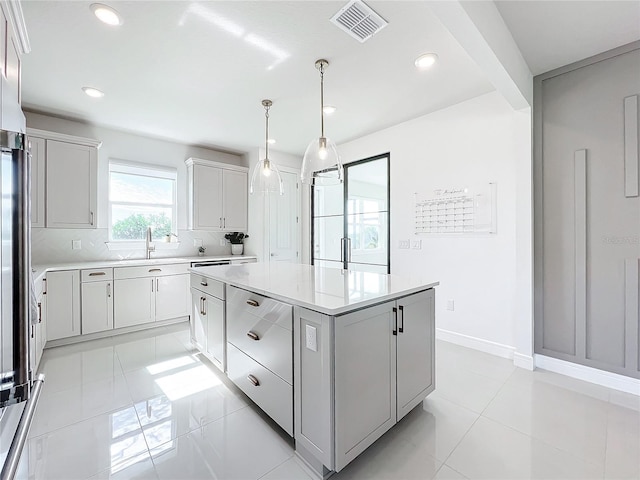 kitchen with sink, hanging light fixtures, light tile patterned floors, tasteful backsplash, and a kitchen island