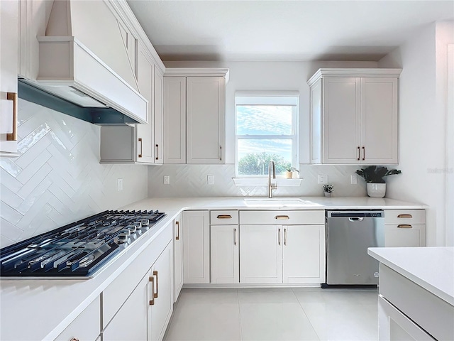 kitchen with white cabinetry, sink, custom range hood, and stainless steel appliances