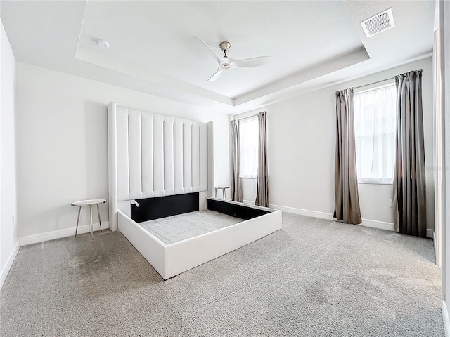 unfurnished bedroom with carpet flooring, a raised ceiling, and ceiling fan