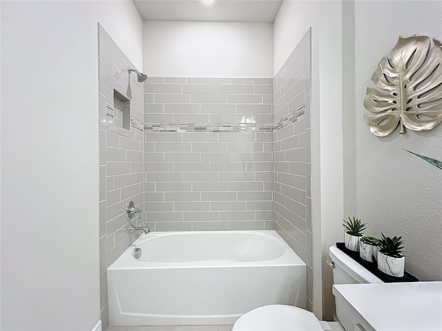 bathroom featuring toilet and tiled shower / bath