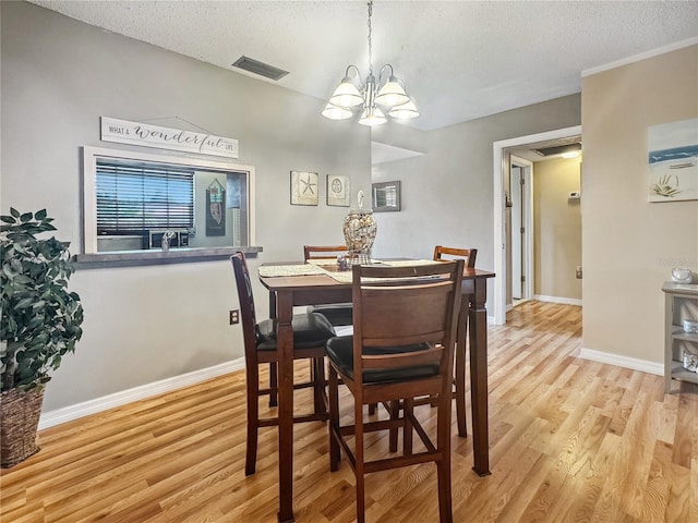 dining space with a notable chandelier, a textured ceiling, and light wood-type flooring