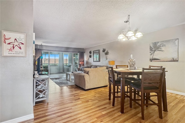 dining area featuring an inviting chandelier, a textured ceiling, and light hardwood / wood-style flooring