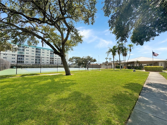 view of home's community with a lawn and tennis court