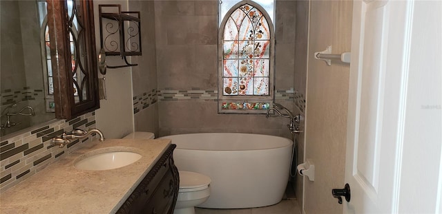 bathroom with a tub, tile walls, decorative backsplash, vanity, and toilet