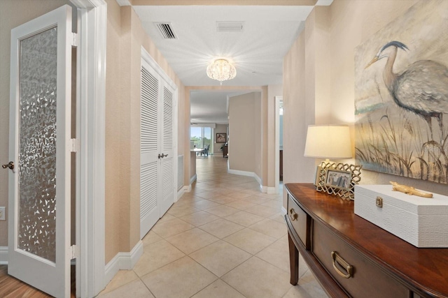 hall featuring light tile patterned floors and a chandelier