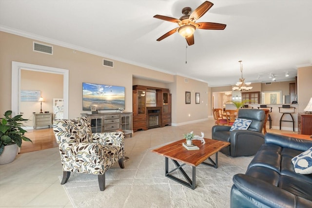 tiled living room with ceiling fan with notable chandelier and crown molding