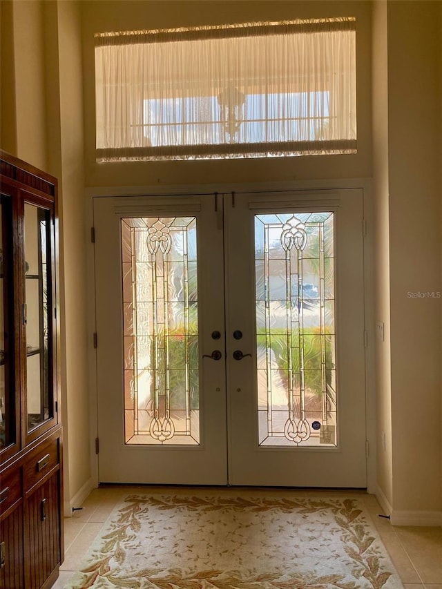 doorway featuring a towering ceiling, french doors, and light tile patterned flooring