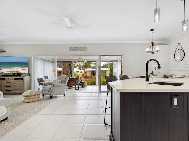 kitchen with pendant lighting, a breakfast bar, sink, ornamental molding, and light tile patterned flooring