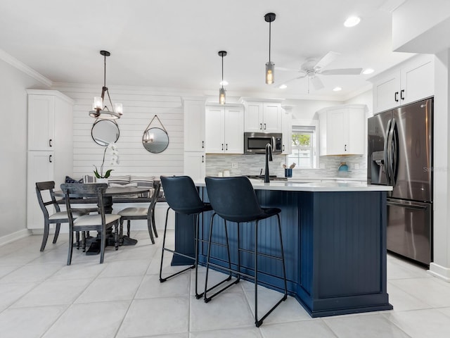 kitchen featuring white cabinetry, hanging light fixtures, a kitchen island with sink, ceiling fan with notable chandelier, and appliances with stainless steel finishes