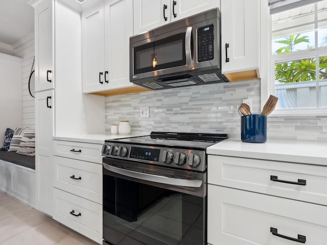 kitchen with tasteful backsplash, white cabinets, ornamental molding, and electric range oven