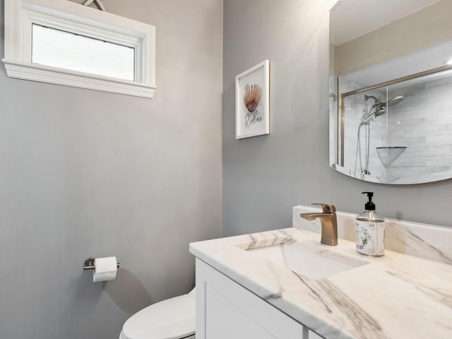 bathroom with tiled shower, vanity, and toilet