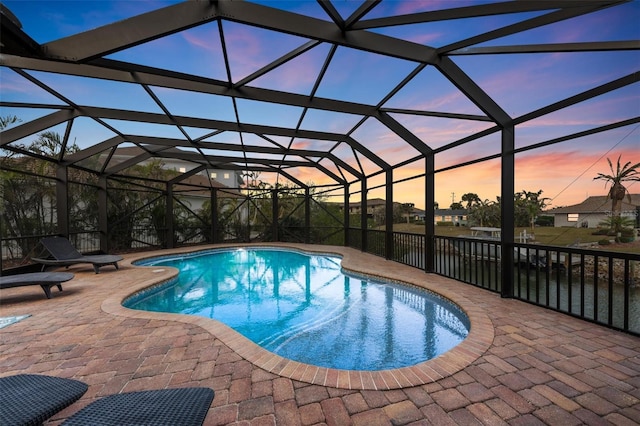 pool at dusk with a lanai and a patio