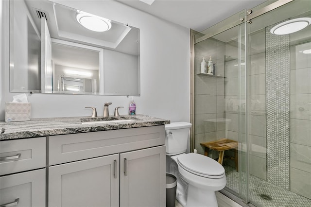 bathroom featuring toilet, vanity, and a shower with shower door