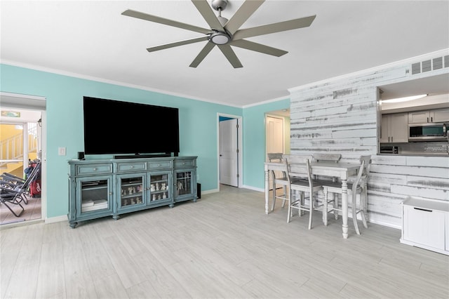 living room with ceiling fan, ornamental molding, and light hardwood / wood-style flooring