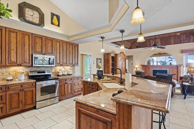 kitchen featuring pendant lighting, a large island with sink, sink, ceiling fan, and stainless steel appliances