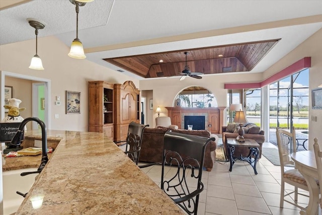 interior space featuring ceiling fan, decorative light fixtures, light tile patterned flooring, wood ceiling, and a breakfast bar area