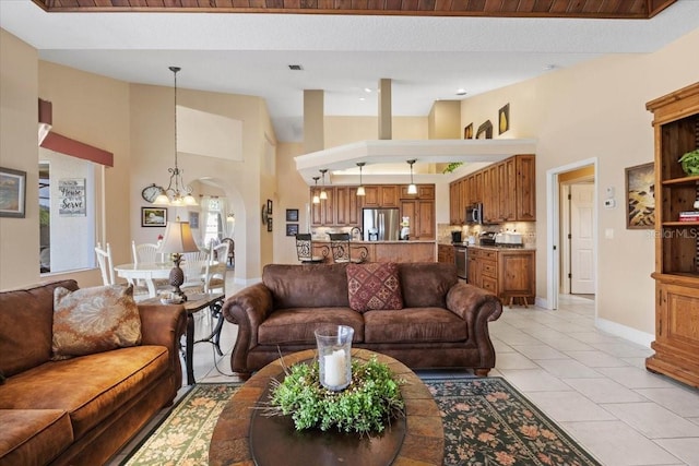 tiled living room featuring a notable chandelier and a towering ceiling