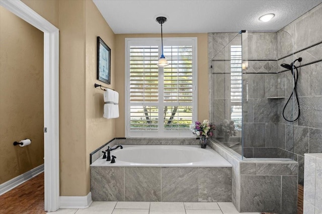 bathroom with tile patterned flooring, plenty of natural light, separate shower and tub, and a textured ceiling