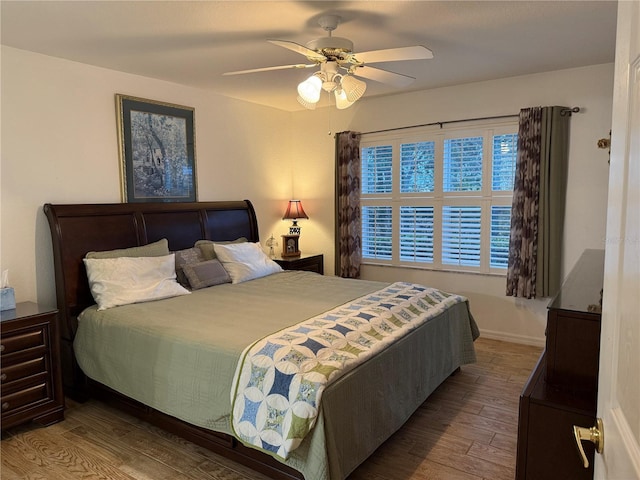 bedroom featuring ceiling fan, multiple windows, and hardwood / wood-style flooring