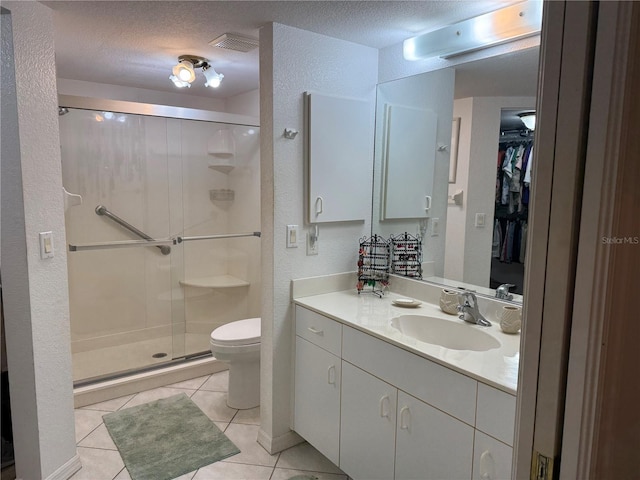 bathroom featuring walk in shower, vanity, toilet, tile patterned floors, and a textured ceiling