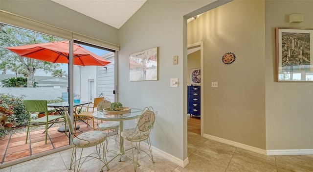 dining area with vaulted ceiling and light tile patterned floors