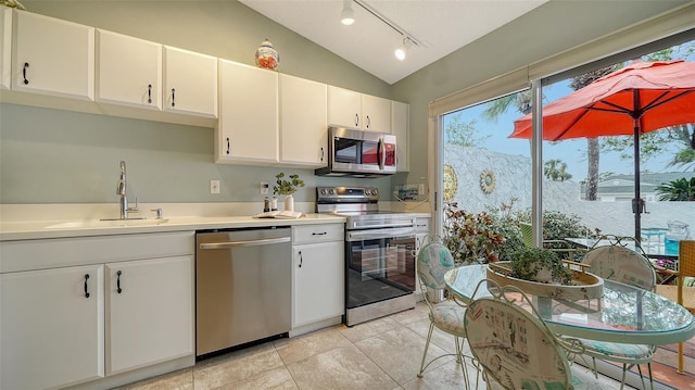 kitchen featuring sink, appliances with stainless steel finishes, white cabinetry, a mountain view, and vaulted ceiling