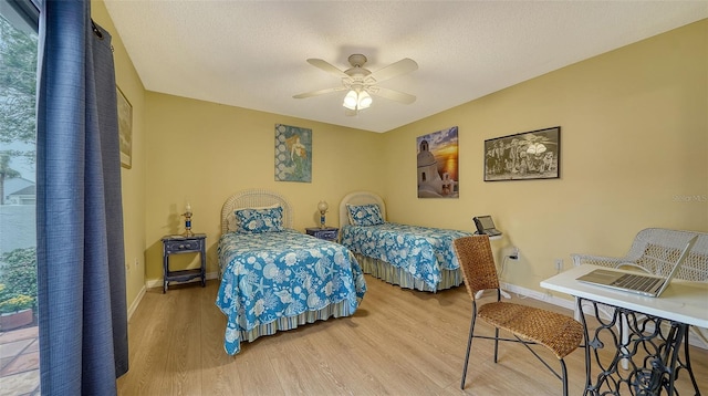 bedroom featuring multiple windows, a textured ceiling, wood-type flooring, and ceiling fan