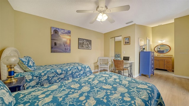 bedroom with ensuite bathroom, ceiling fan, a textured ceiling, light wood-type flooring, and a closet