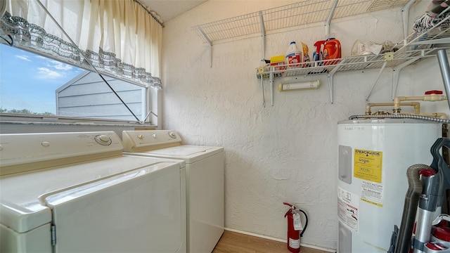 washroom featuring water heater, separate washer and dryer, and hardwood / wood-style flooring