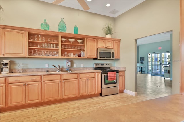 kitchen with stainless steel appliances, sink, light brown cabinets, and a high ceiling