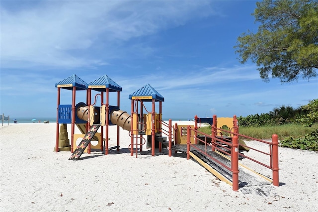 view of playground featuring a water view and a beach view