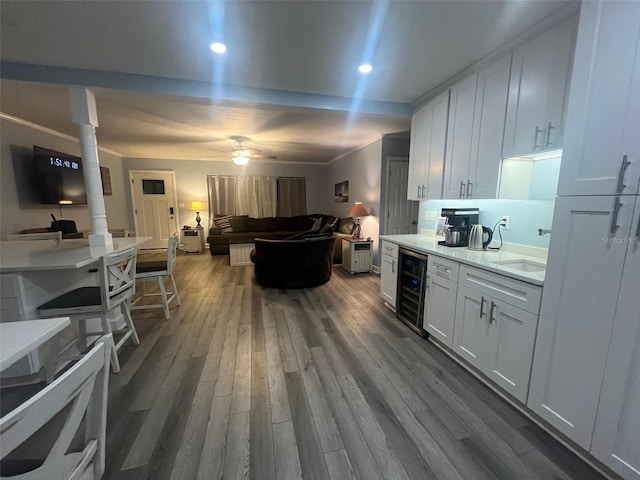 kitchen with ceiling fan, sink, hardwood / wood-style flooring, white cabinets, and wine cooler