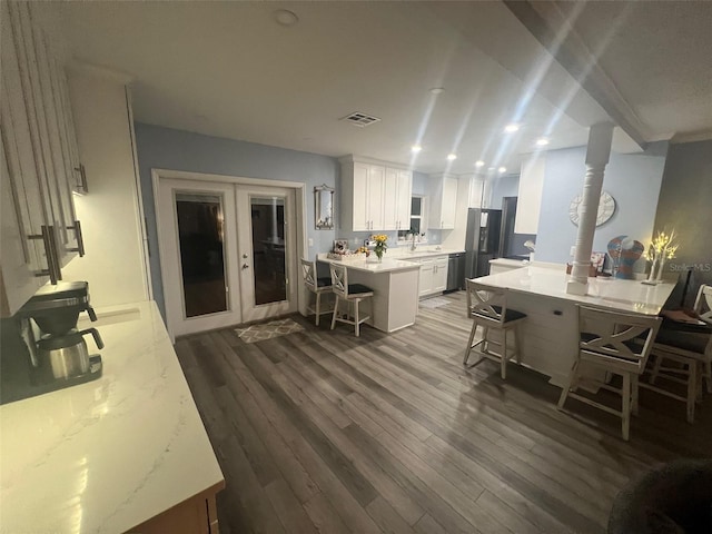 kitchen featuring stainless steel refrigerator, sink, kitchen peninsula, a breakfast bar area, and white cabinets