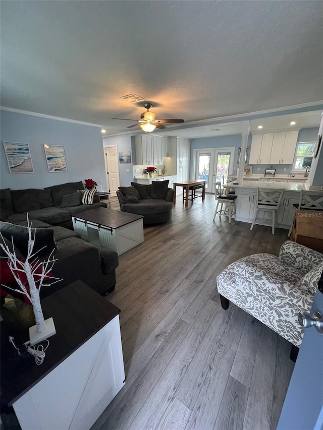 living room with ceiling fan, light wood-type flooring, ornamental molding, and french doors