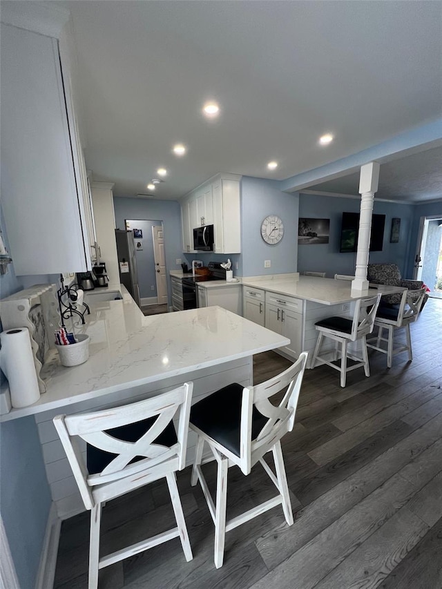 kitchen with kitchen peninsula, white cabinets, black electric range, and a breakfast bar area