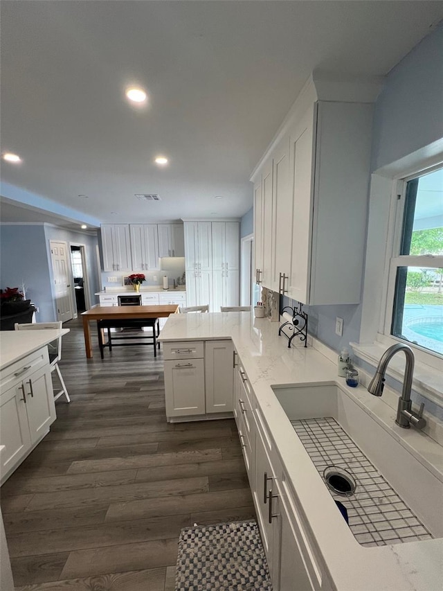 kitchen featuring kitchen peninsula, sink, white cabinets, and dark wood-type flooring