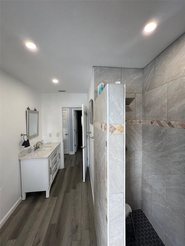 bathroom with vanity, a tile shower, and wood-type flooring