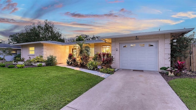 single story home featuring a garage and a yard