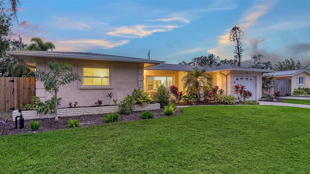 view of front facade featuring an attached garage, fence, concrete driveway, stucco siding, and a front yard