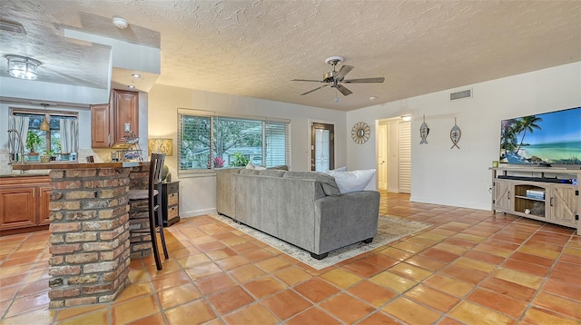 living room featuring a ceiling fan, light tile patterned flooring, visible vents, and a healthy amount of sunlight