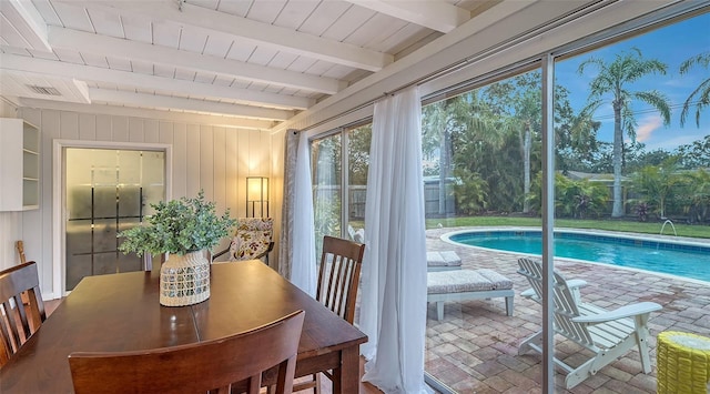 dining space featuring wooden walls, visible vents, wooden ceiling, brick floor, and beam ceiling