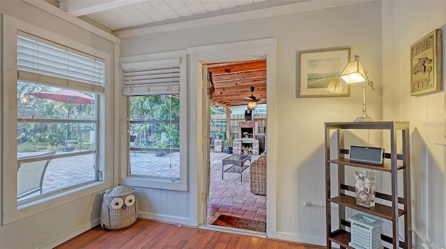 doorway featuring a ceiling fan, a fireplace, baseboards, and wood finished floors