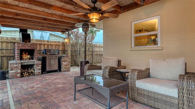 view of patio featuring an outdoor brick fireplace, a grill, fence, and ceiling fan