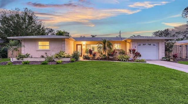 single story home featuring concrete driveway, an attached garage, fence, a front lawn, and stucco siding